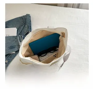 Detailed interior view of a white canvas tote bag showing storage for tablet and phone