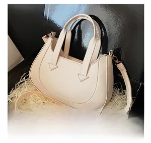 Close-up of a cream crescent handbag in a premium black gift box with adjustable strap