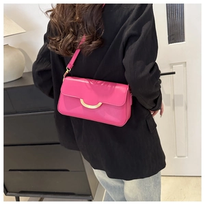 Detail showing magenta leather crossbody bag with golden crescent buckle on black blazer