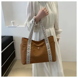 Close-up of brown tote bag with geometric woven handle and side pockets detail