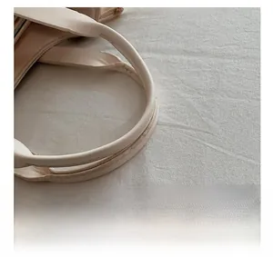 Close-up of beige leather handbag handle with fine stitching and soft texture