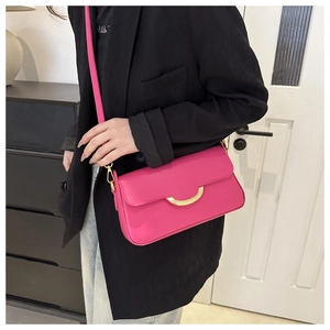 Detail of rose pink crossbody bag with large gold arch buckle and fine faux leather texture
