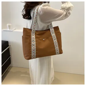 Detail of caramel tote bag showing geometric rhombus shoulder strap and snap button pocket