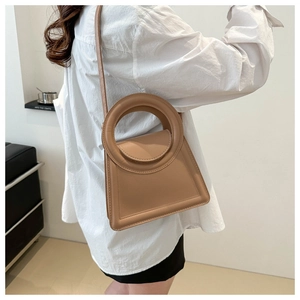 Detail of khaki trapezoid handbag with a large circular handle and adjustable shoulder strap