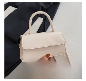 Detail view of the cream white PU leather handbag with top handle and magnetic flap closure