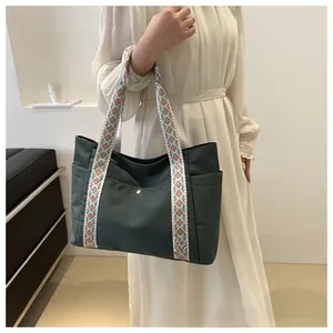 Detail view of large dark green tote bag featuring bohemian embroidered wide straps