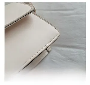 Close-up of precise stitching and premium leather texture on a beige underarm bag
