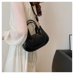 Detail view of the sleek black crescent shoulder bag with golden metallic hardware