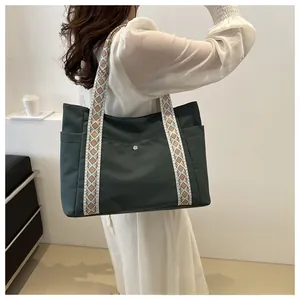 Detail of dark green tote bag with ethnic geometric wide straps and utility pockets