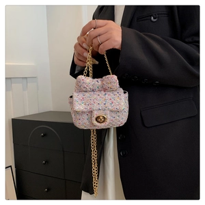 Detail of pink tweed mini bag featuring a decorative bow and gold chain strap