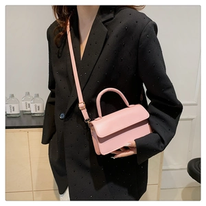 Detail of light pink mini leather handbag with round handle and adjustable shoulder strap