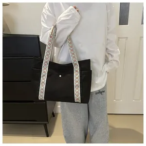 Detail of black tote bag with bohemian geometric woven shoulder strap and metal snap button