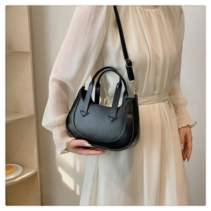 Chic black crescent bag shown with a white dress, highlighting its elegant shape and strap