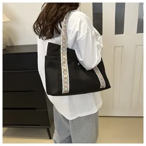 Detail of black canvas tote bag featuring a colorful ethnic geometric shoulder strap