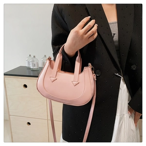 Detail view of pink semi-circular handbag with PU leather texture and strap