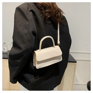 Detail of a beige mini flap shoulder bag paired with a black sequin blazer on a model