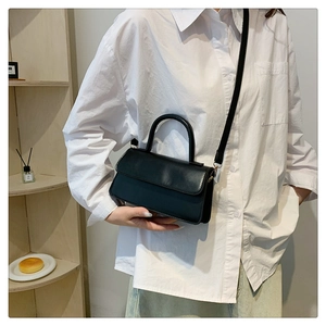 Classic black leather shoulder bag styled with a white shirt in a minimalist home setting