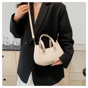 Close-up of a cream-colored PU leather handbag with detachable strap and shoulder carry