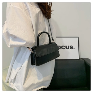 Side view of a vintage black square underarm bag showing the texture and metal hardware