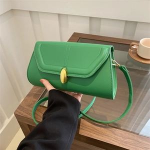 Sac baguette minimaliste en cuir vert avec boucle dorée dans un cadre lifestyle
