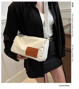 Detail view of off-white crossbody bag with colorful woven strap and leather logo patch
