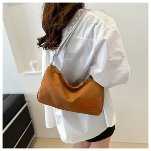 Detail of caramel crossbody bag featuring ethnic style wide strap and fashion logo patch