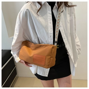 Detail of caramel crossbody bag with a wide ethnic style strap and fashion label