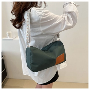 Detail of green cylinder crossbody bag with geometric jacquard wide strap on model