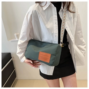 Detail of dark green nylon shoulder bag with orange label and ethnic pattern strap