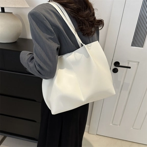 White vintage large leather tote bag worn by a model in a modern indoor setting