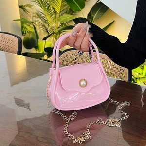 Pink jelly tote bag with pearl buckle and gold chain strap in a cafe setting