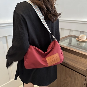 Red casual crossbody bag with ethnic pattern wide shoulder strap in home setting
