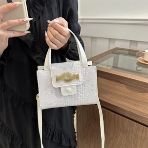 White faux crocodile leather handbag with elegant gold wavy clasp held by a model