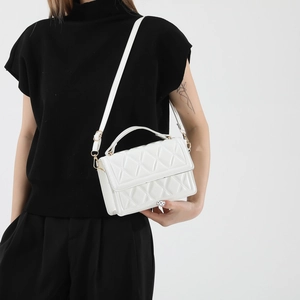 Elegant white quilted crossbody bag with gold hardware shown on a model in minimalist style