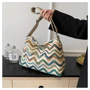 Détail d'un sac cabas en maille à motifs ondulés avec deux bandoulières porté