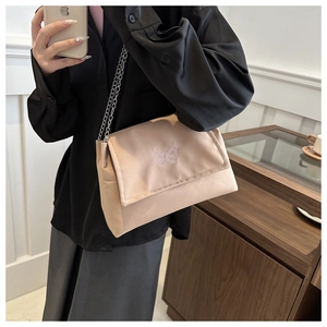 Détail de la broderie papillon sur un sac à bandoulière en tissu marron clair avec chaîne