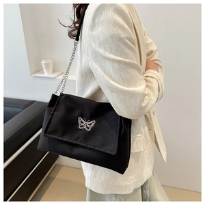Detail of black canvas shoulder bag with white butterfly embroidery and silver chain