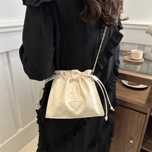Quilted cream drawstring bucket bag with triangular plaque and metal chain strap
