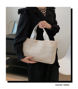 Detail of woven straw tote bag with white canvas handles for summer beach fashion