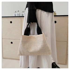 Close-up of the woven straw texture and durable black fabric handles on the tote bag
