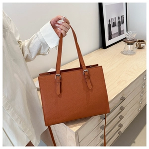 Close-up of a brown tote bag with leather texture and buckle details in a lifestyle setting