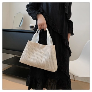 Detail of cream woven tote bag featuring thick fabric handles and textured mesh material