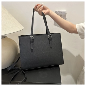 Detail of black tote bag featuring saffiano leather texture and adjustable silver buckles