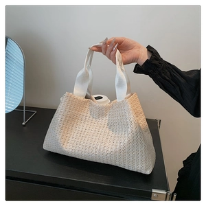 Detailed close-up of woven beige straw tote bag with white fabric handles for casual look