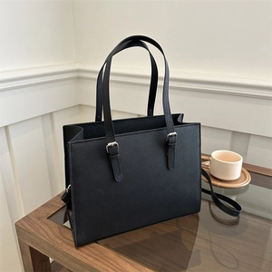 Detail view of black Saffiano leather tote bag featuring adjustable silver buckle straps