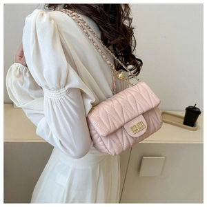 Detail of light pink quilted saddle bag with gold chain strap and twist lock closure