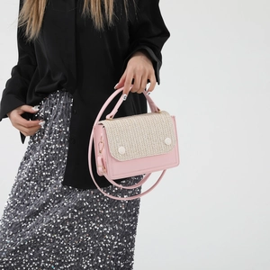 Pink and beige woven crossbody bag with chain strap and handle in minimalist setting