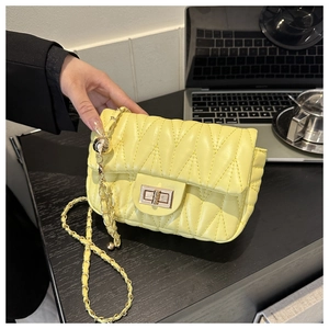 Detailed shot of yellow quilted saddle bag featuring V-stitch texture and gold chain strap