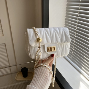 Close-up of white quilted saddle bag with gold chain strap and adjustable golden ball
