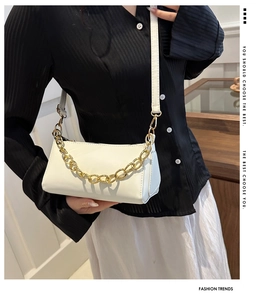 Detail of creamy white crossbody bag with decorative gold chain and slim leather strap